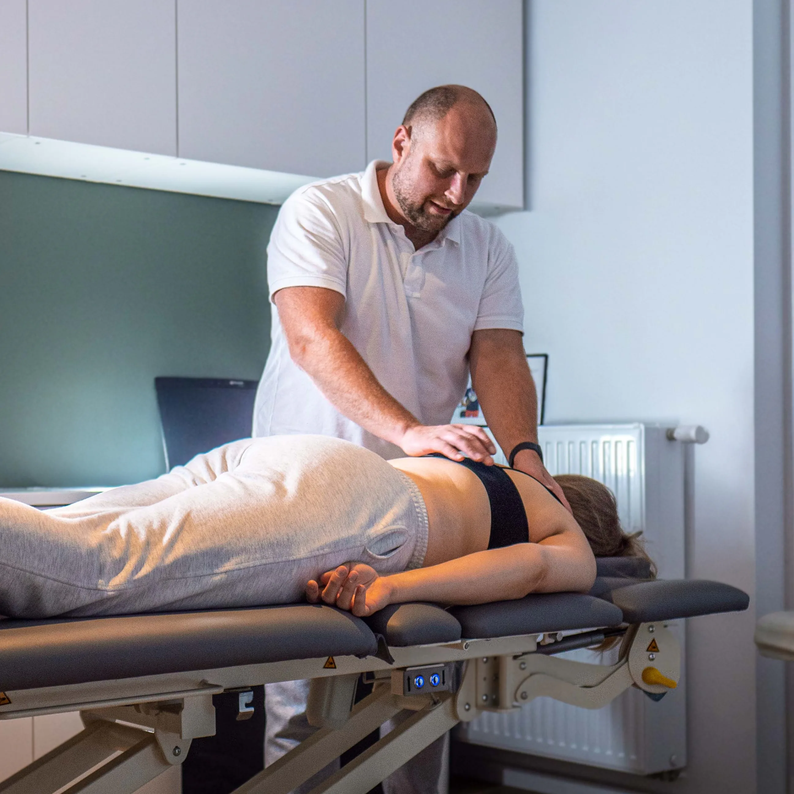 Physiotherapist supporting a patient during rehabilitation on a stationary bike